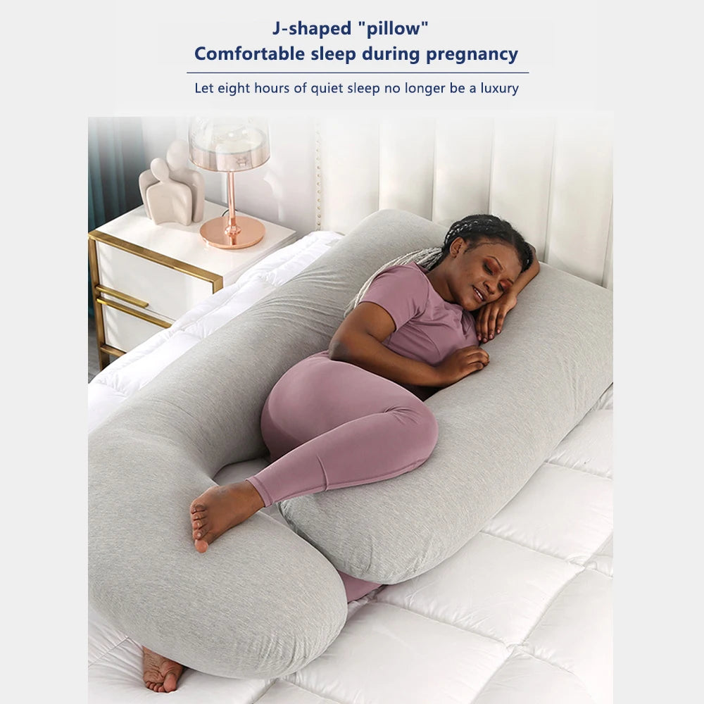 Pregnant woman using a J-shaped pillow for comfortable sleep.