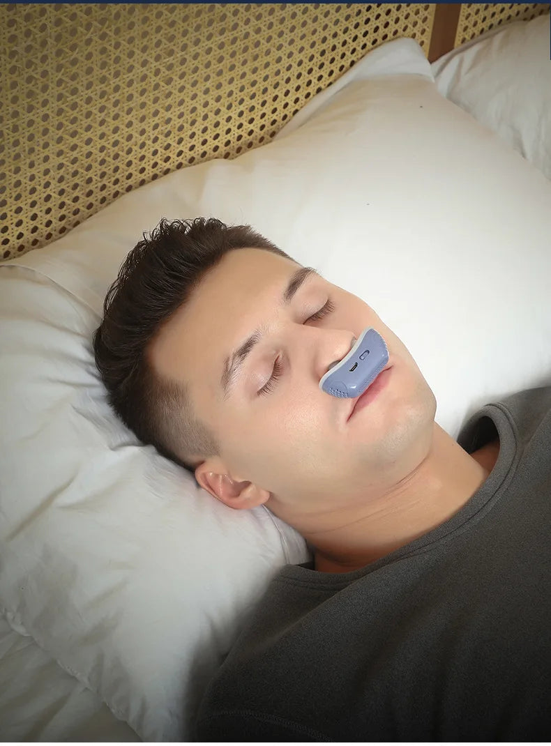 Man lying in bed with blue electronic anti-snoring device in his nose.
