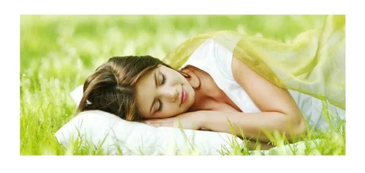Woman lying on a white pillow in a grassy field