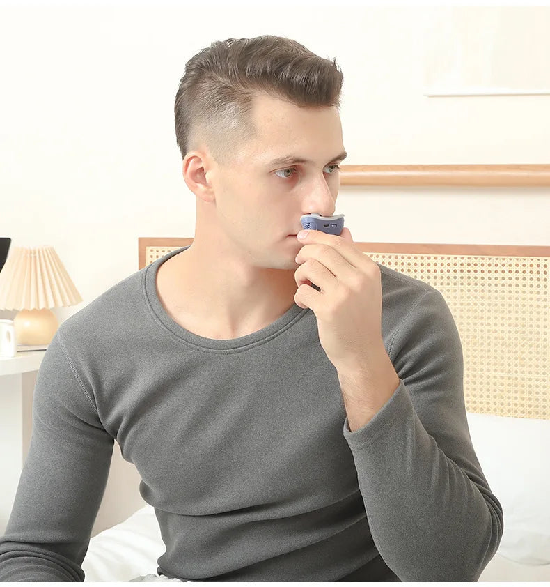 Man in a grey shirt fitting an anti snoring device in a room.