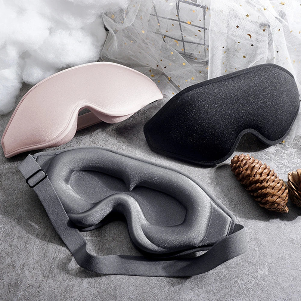 Three sleep masks in a variety of colours - gray, black, and pink.