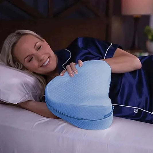 Woman in bed holding a blue heart-shaped pillow.