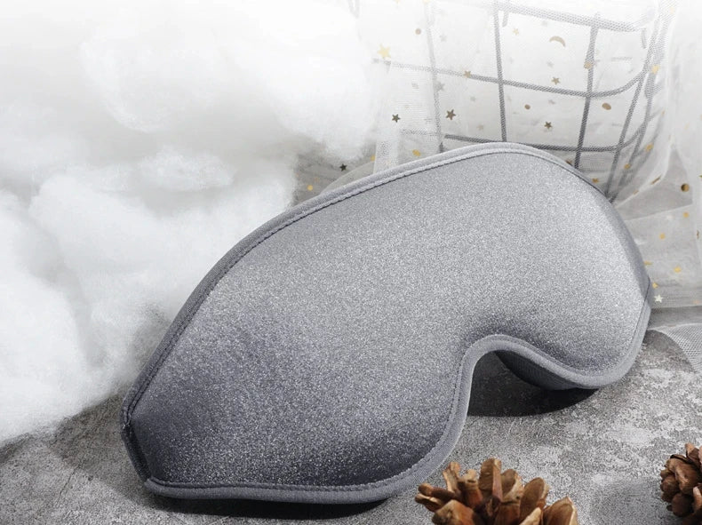 Gray eye mask on a textured surface with a soft white background