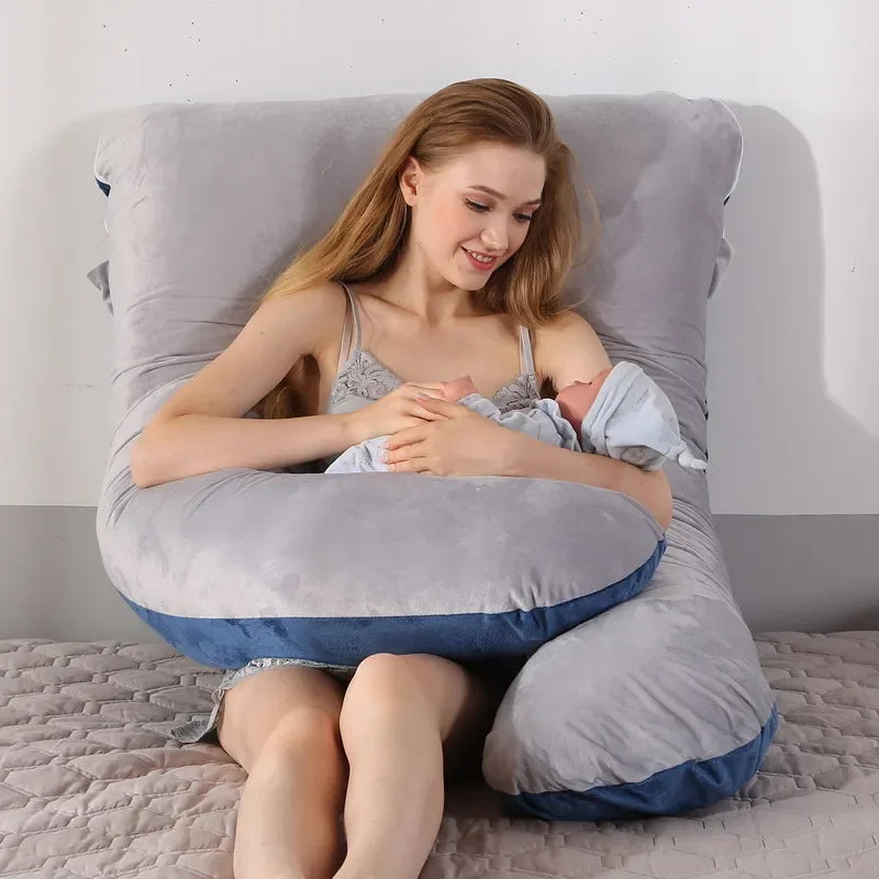 Mother using the large U-shaped grey pillow to cushion the baby. Easy for carrying baby.
