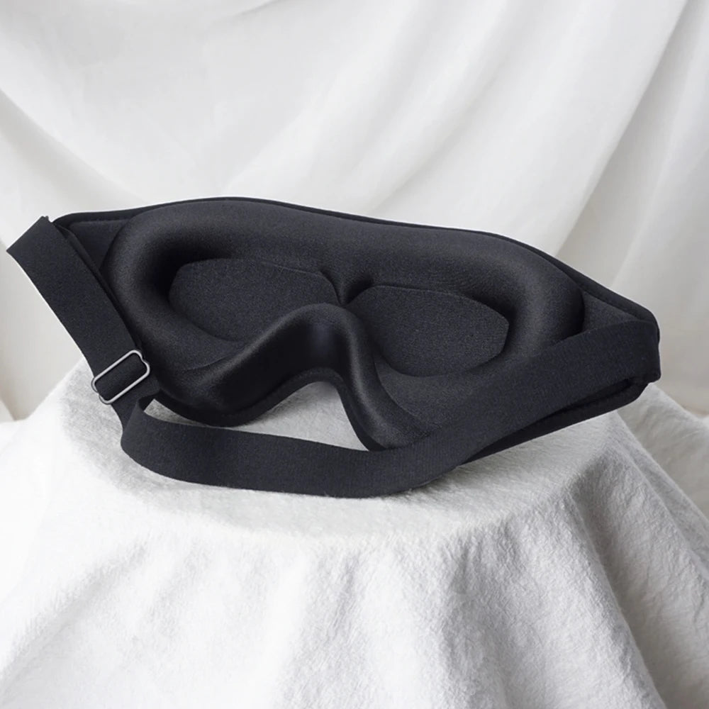 Black sleep mask on a white fabric background