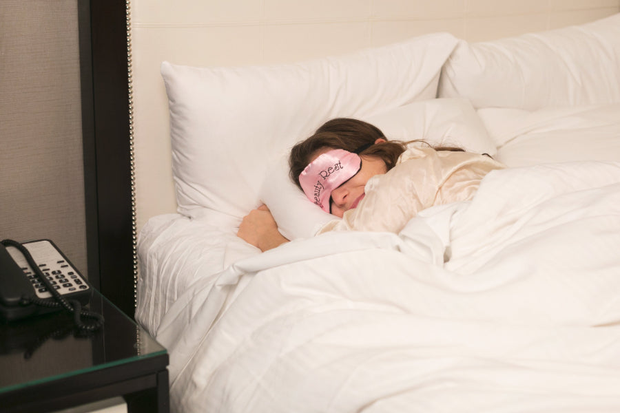 Lady sleeping on bed with a sleep mask.