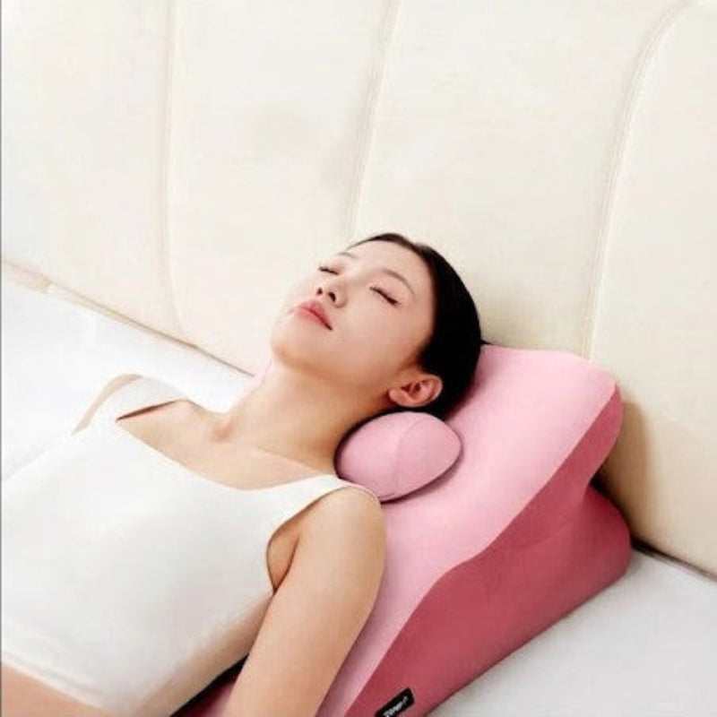Woman lying on a pink wedge-shaped pillow against a white background
