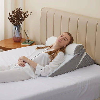 Woman using a wedge pillow in bed with a beige headboard and wooden nightstand.