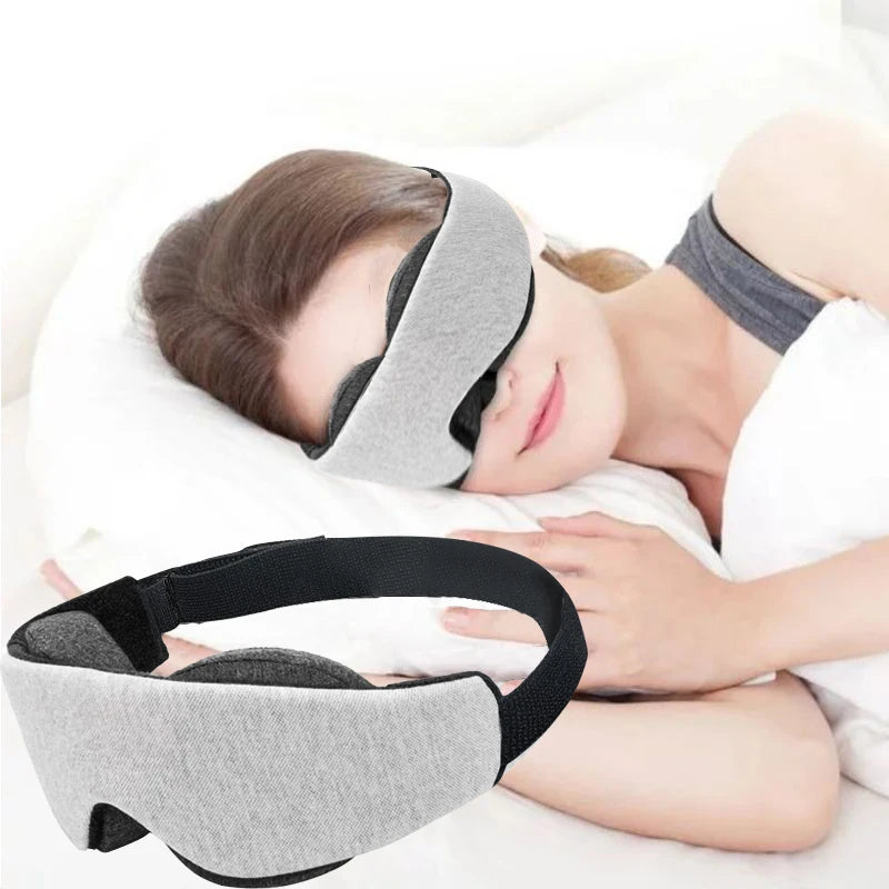 Woman using a grey and black sleeping eye mask while lying down.