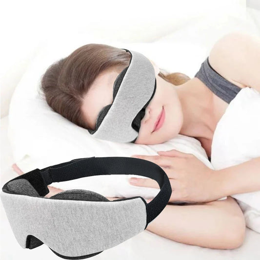 Woman using a grey and black sleeping eye mask while lying down.