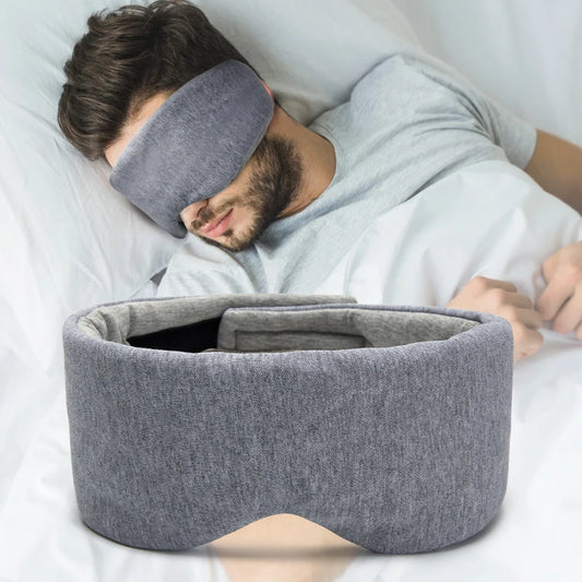 Man sleeping and wearing a grey extra large eye mask to block out light.