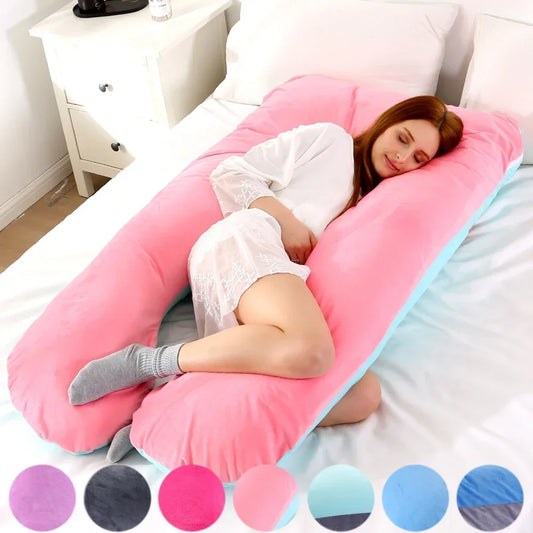 Pregnant maternity woman lying on a pink U-shaped body pillow in a bedroom.