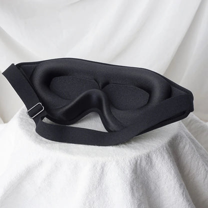 Black sleep mask on a white fabric background