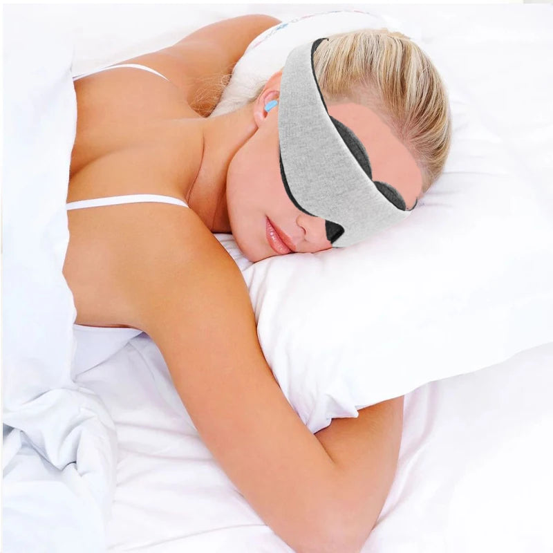 Woman wearing a grey sleeping eye mask while lying on a pillow.