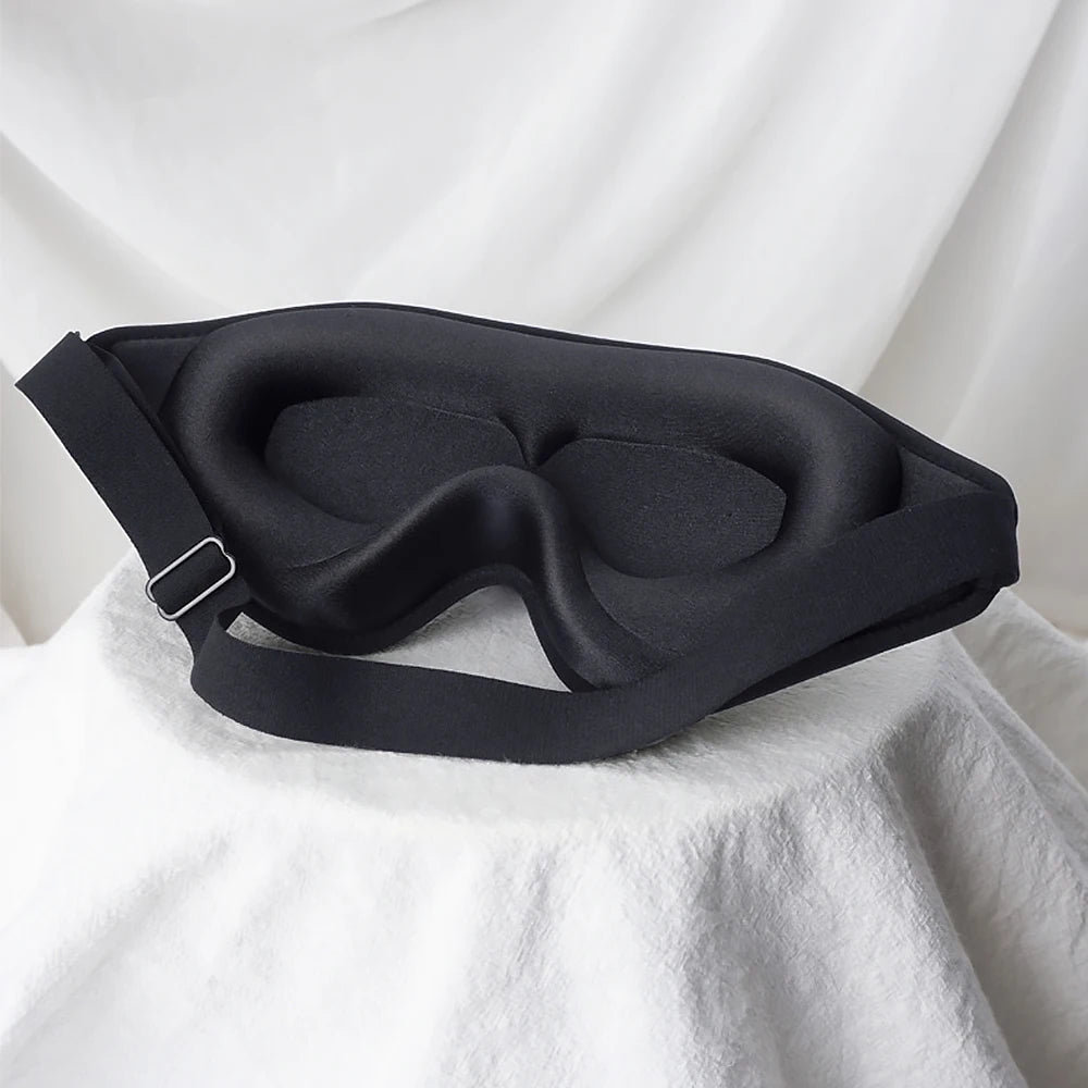 Black sleep mask on a white fabric background