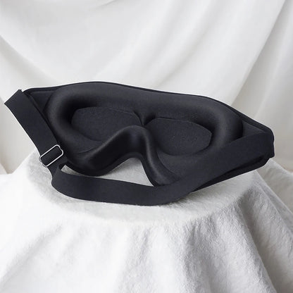 Black sleep mask on a white fabric background