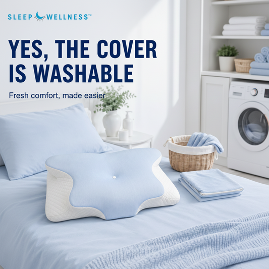 A light blue and white contoured pillow on a bed in a bright bedroom setting, with text reading 'YES, THE COVER IS WASHABLE' and the brand 'SLEEP WELLNESS' at the top.